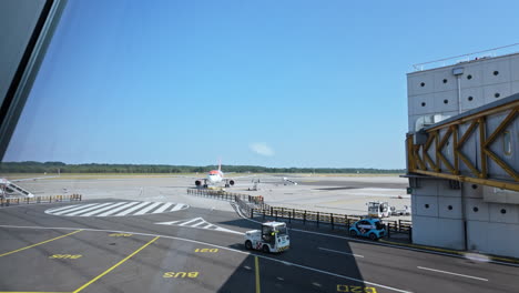 a parked airplane on a sunny day at the airport, with ground vehicles moving on the runway