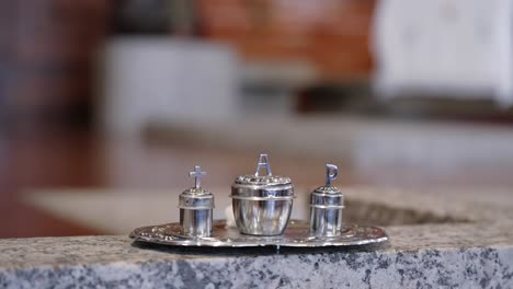 close up silver holy oils containers set on tray for religious ceremonies