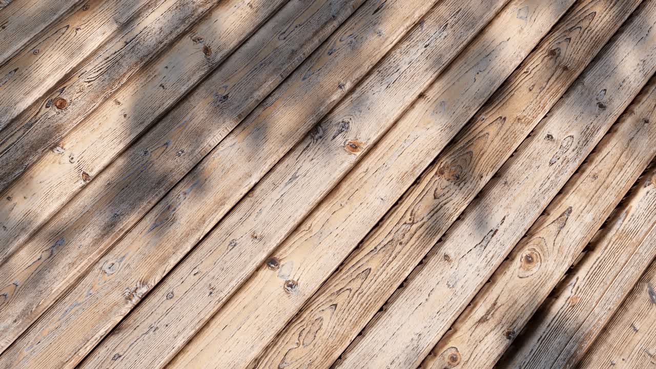 Bevægelige skygger på vejrbidte træplanker i sollys