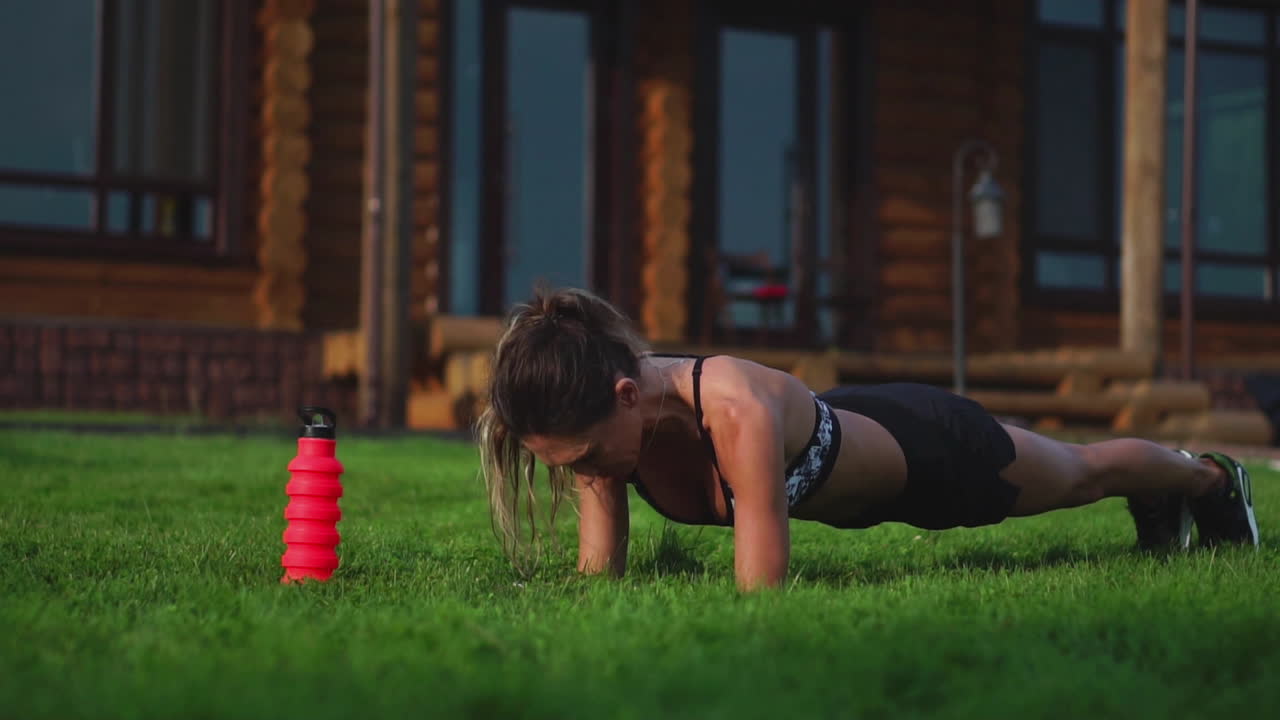 뜨거운 여름날 공원에서 바 ⁇ 에서 보드 운동을 하는 적합한 소녀