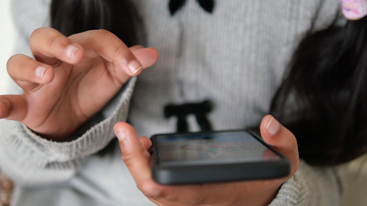 Child's Hands Playing Mobile Game on Smartphone