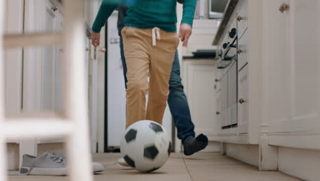 père et fils jouant au football dans la cuisine kicking ballon de football enfant appréciant le jeu avec le père à la maison