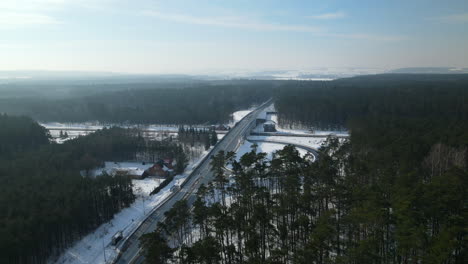 aerial view of traffic on polish autostrada surrounded by pine tree forest during sunny day in winter