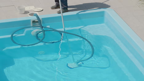 A-man-in-overalls-cleans-a-home-pool.-View-from-above.-Tilt-shot