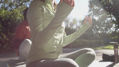 low section of diverse couple practicing yoga meditation sitting out in sun, copy space, slow motion