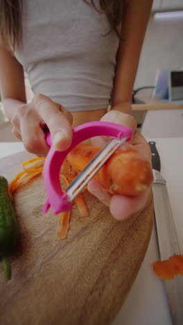 person peeling a carrot in a kitchen