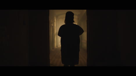 a girl and strange clown on stilts in a dark corridor at night