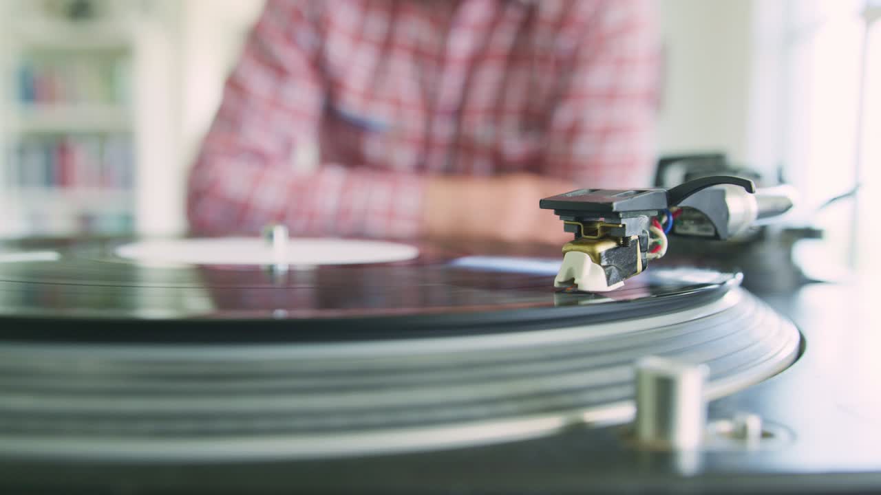 레코드와 스타일러스 바늘을 턴테이블에 넣는 남자