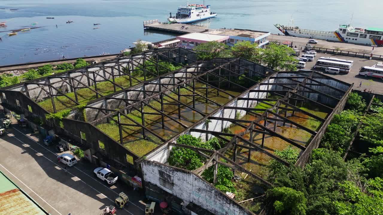 Aerial Forward Shot of Roofless, Abandoned Warehouses at Tabaco Port, Philippines.