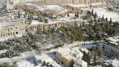 aerial view overlooking snowy ruins, houses and trees after a rare snow storm, in sunny athens, greece - circling, drone shot