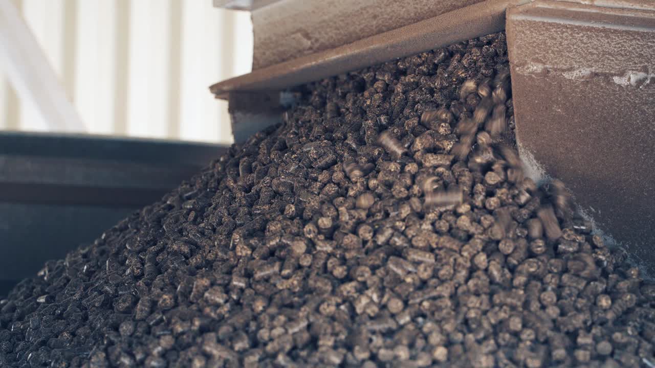 Pressed wooden briquettes coming out of the industrial equipment. Biomass fuel and environmental protection concept. Close-up