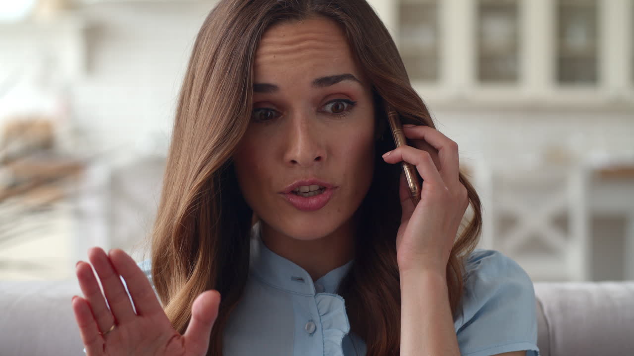 Young business woman having unpleasant conversation on phone at home office.