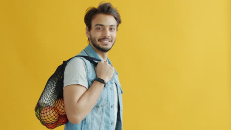 man with a mesh bag carrying fruits