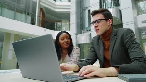 Diverse-Colleagues-Using-Laptop-and-Talking-at-Work