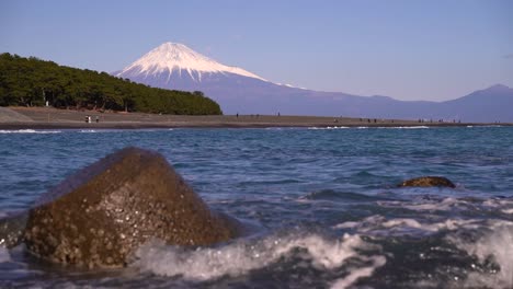 slow motion waves breaking with backdrop of mount fuji on clear day