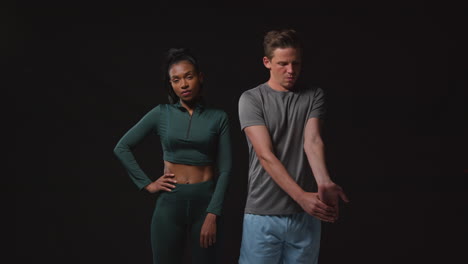 studio portrait of serious and determined male and female athletes training in fitness clothing shot against black background 1