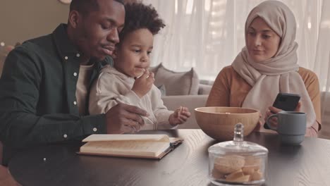 interracial muslim couple with toddler son counting bills and expenses