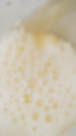 pouring fresh beer with fluffy froth into glass macro upper view. swirling flow of organic alcohol drink with bubbling foam slow motion