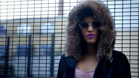 stylish fashion blogger stands by fence in urban street