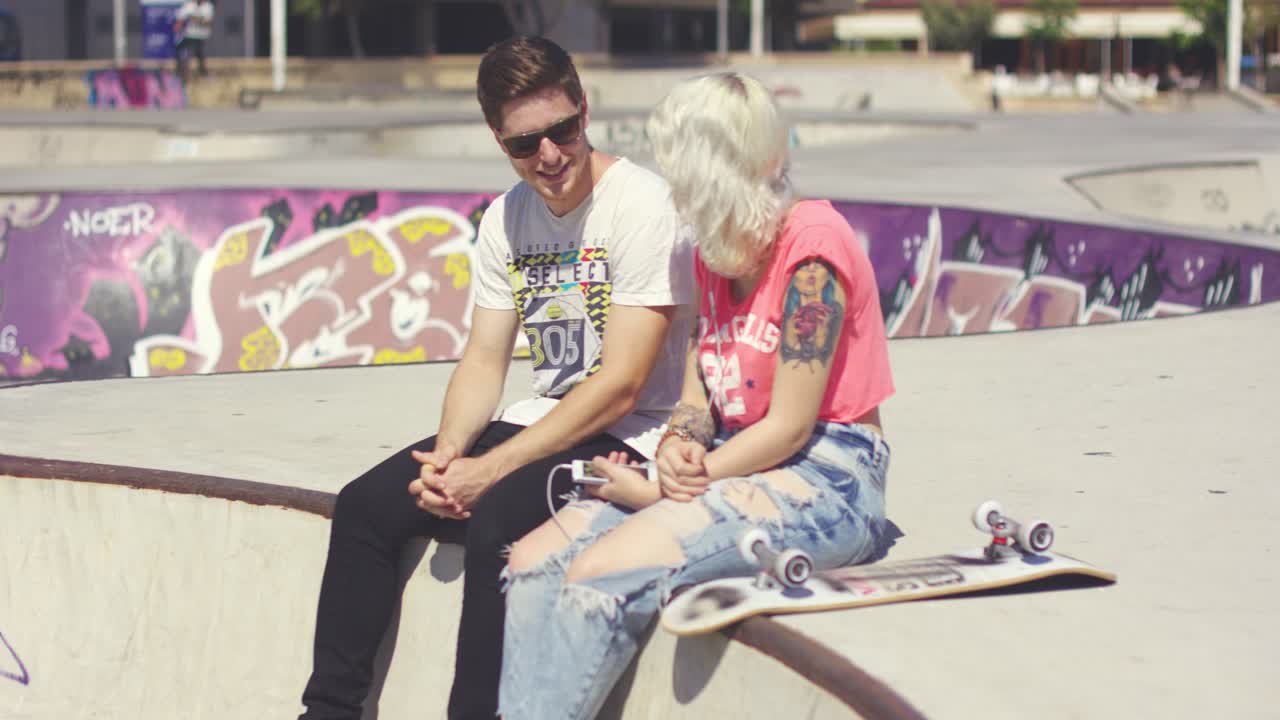 Man chatting to his girlfriend at a skate park
