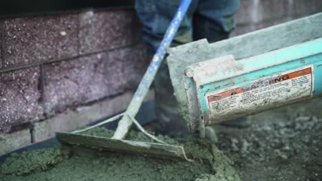 Concrete-cement-pouring-down-chute,-construction-worker-spreading-it-out-on-floor