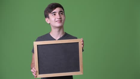 young handsome iranian teenage boy against green background