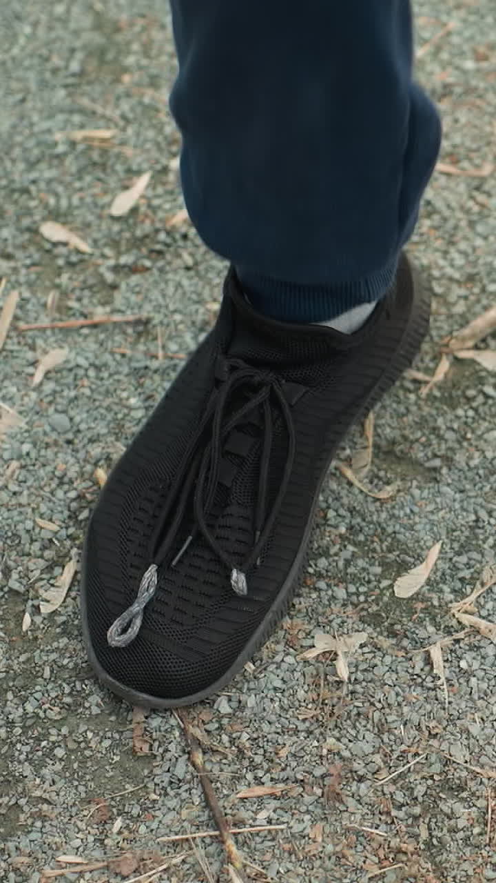 Close-up view of someone squatting up and down wearing a gray top and a black sneakers, as he stretches his hand forward