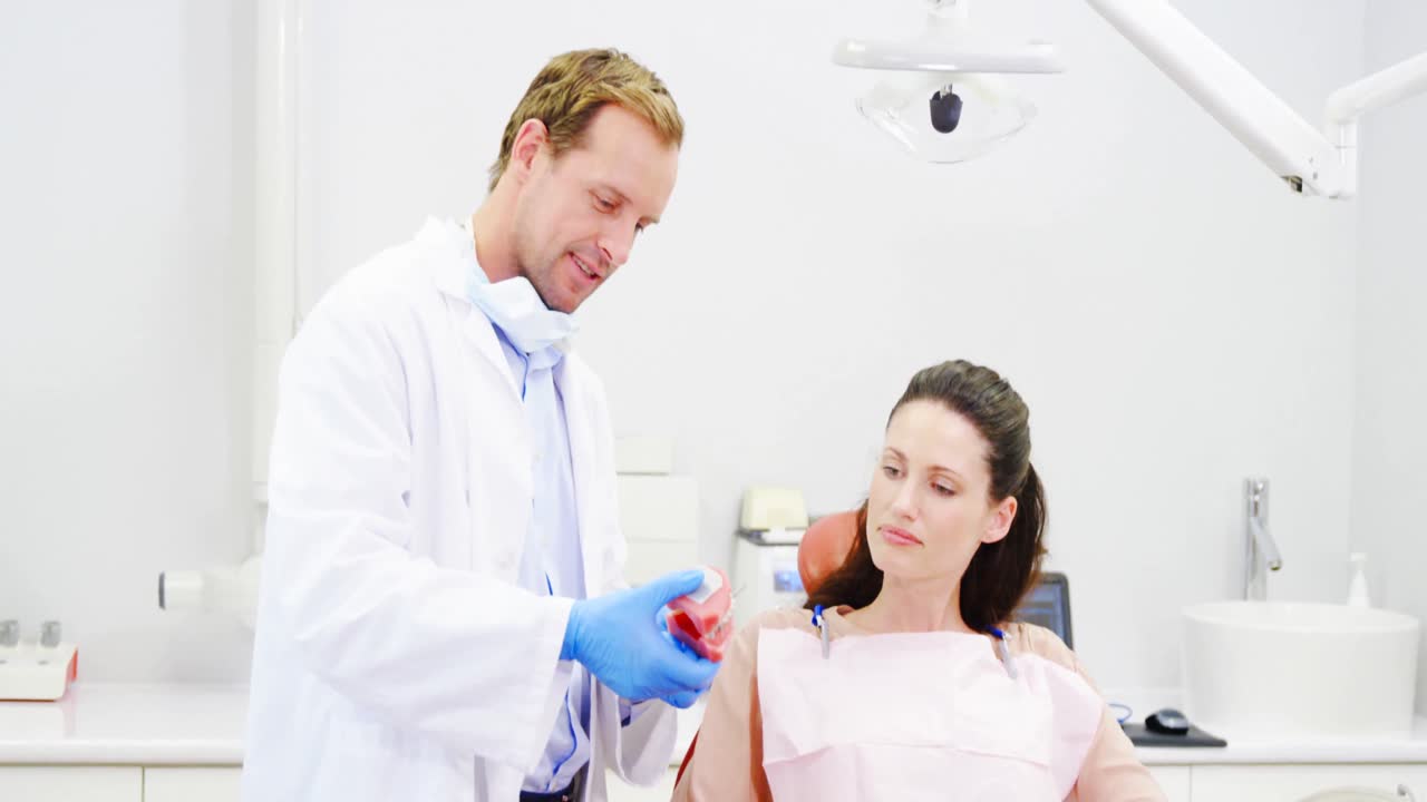Dentist showing model teeth to patient