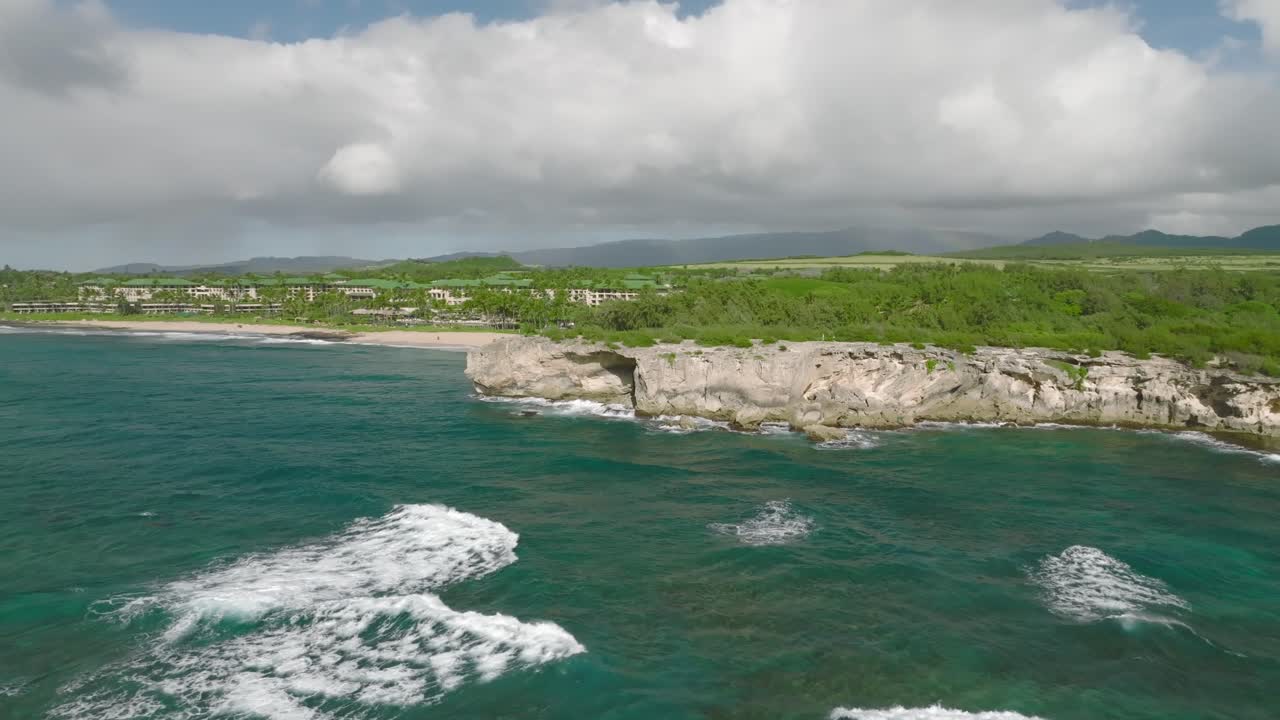 disparo aéreo amplio y lento que orbita alrededor del acantilado desde la distancia en shipwreck beach, hawai