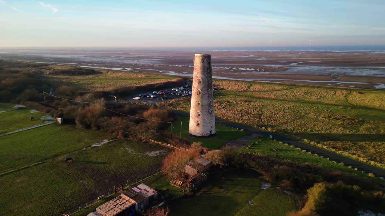 Beautiful aerial drone fast clockwise pan of Leasowe Lighthouse at sunset in winter, UK