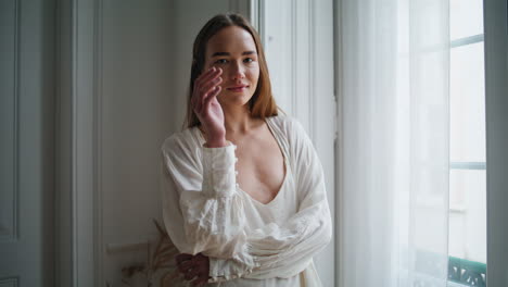 Gorgeous-woman-posing-camera-at-windows-interior-portrait.-Lady-straightens-hair