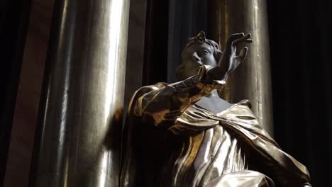 estatua de un hombre con una túnica dorada con la mano levantada