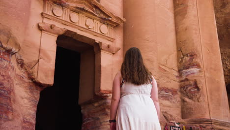 female in white dress walking in the ancient city of petra in jordan - rear view