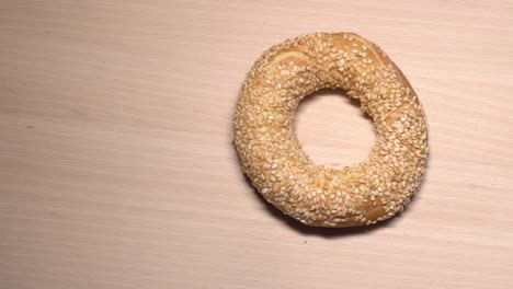 fresh bagels with sesame seeds in rotation. on wooden cutting board. extreme closeup.