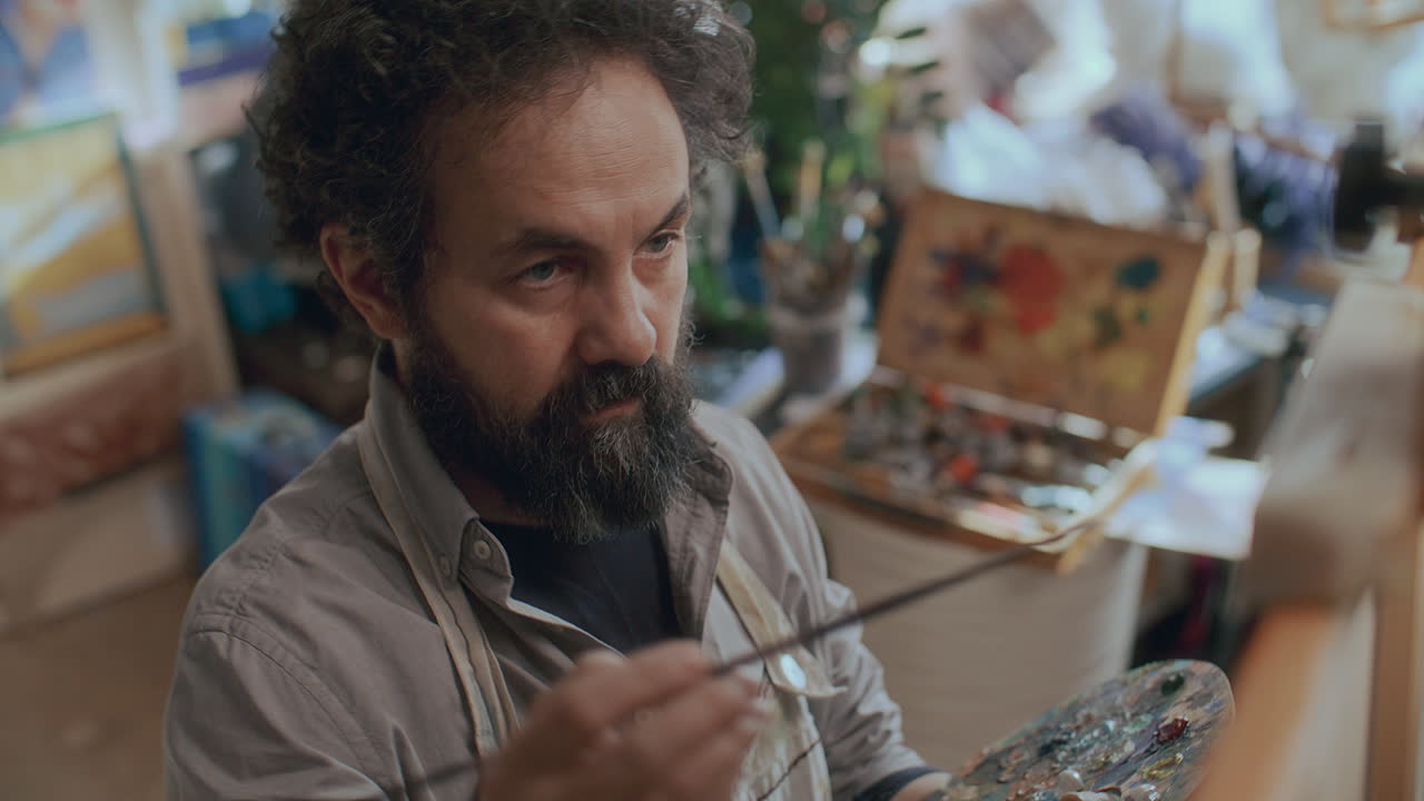 Konzentrierter männlicher Maler arbeitet an einem Kunstwerk im kreativen Atelier