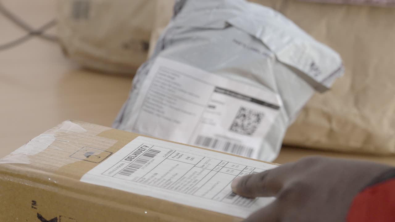 Gig worker scanning QR code of a parcel at warehouse, Closeup
