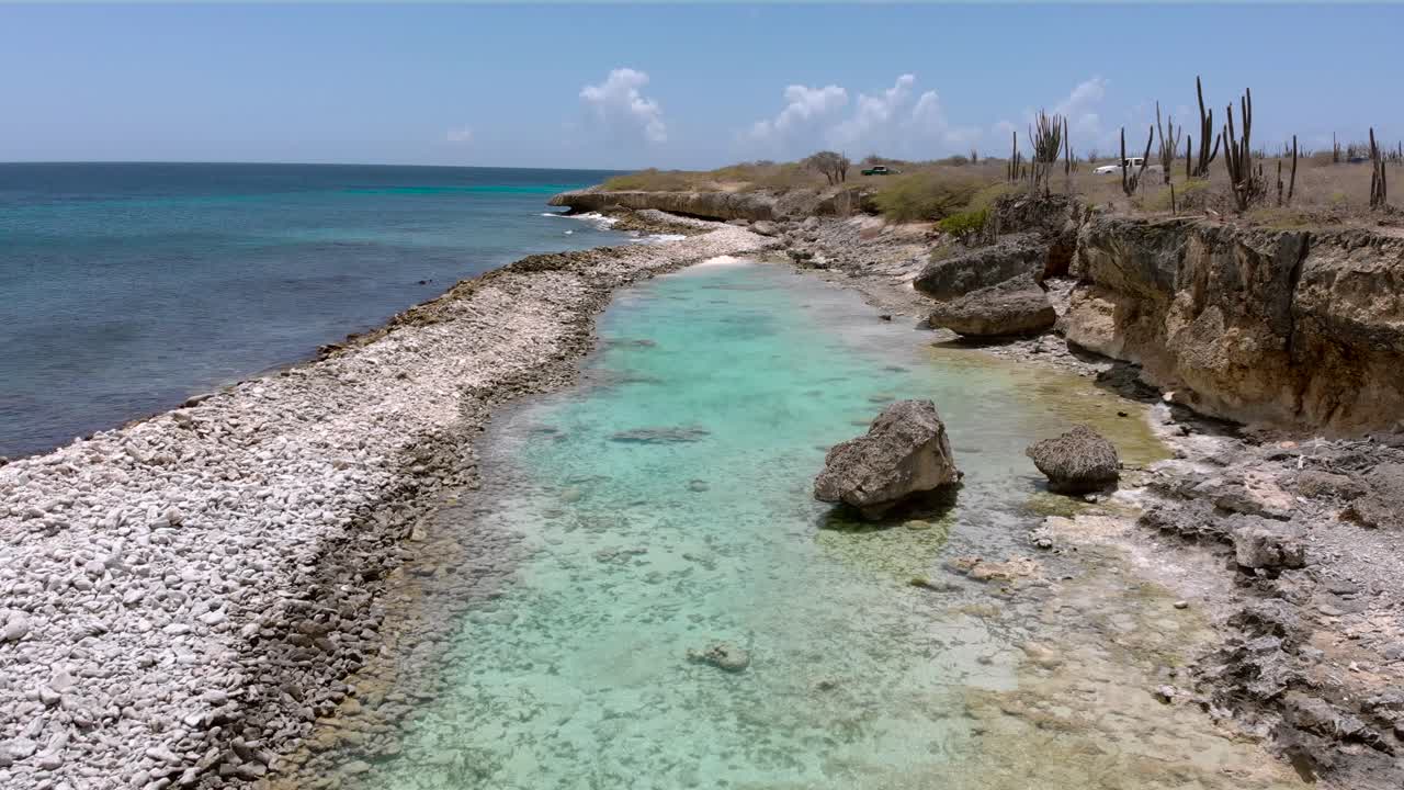 카리브해 섬에 있는 낙원의 작은 청록색 물 석호 위로 천천히 날아갑니다.