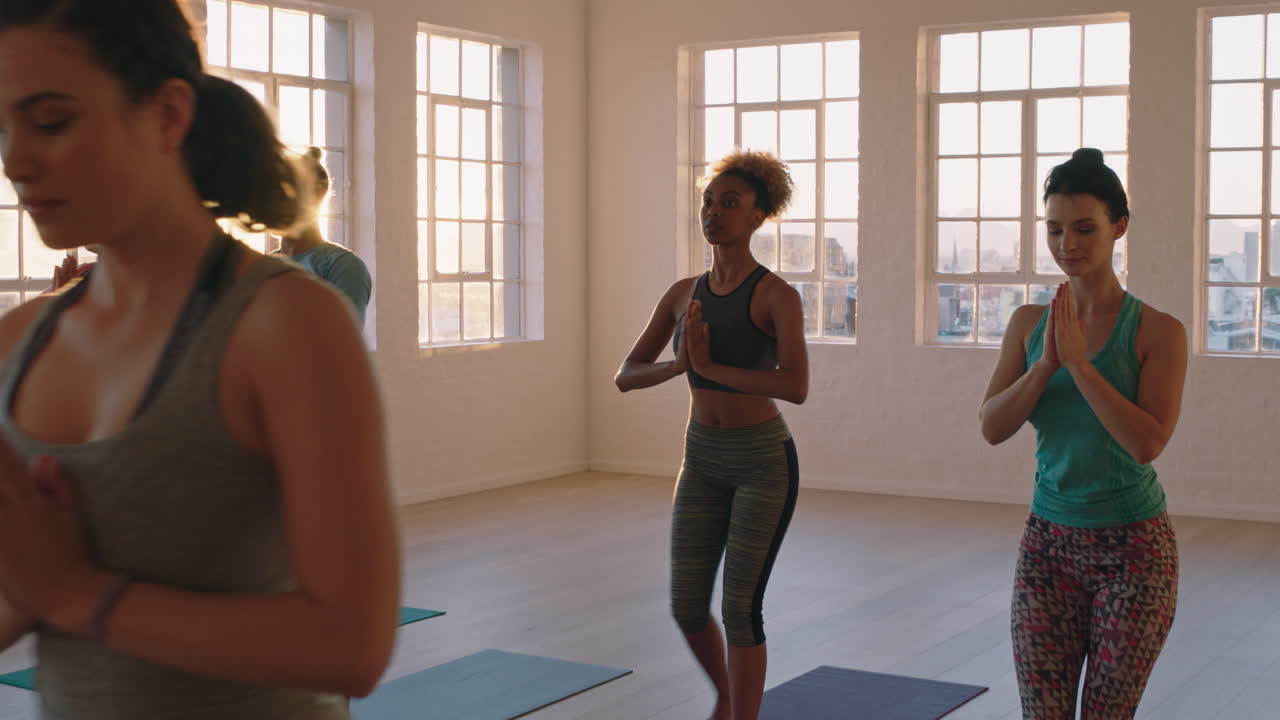 yoga class of young healthy people practicing warrior pose instructor woman teaching diverse group enjoying fitness lifestyle exercising in studio at sunrise