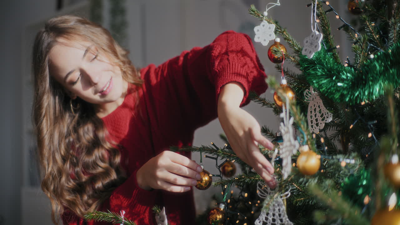 feliz mujer hermosa decorando el árbol de navidad en un hogar brillante