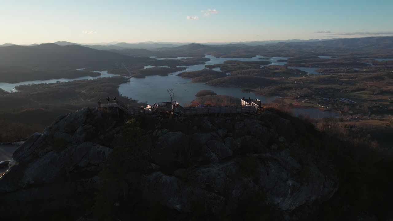 An epic sunset aerial over Bell Knob lookout, a popular hiking location for panoramic views, with a vast landscape of finger lakes around Lake Chatuge in the north Georgia mountains near Hiawassee.