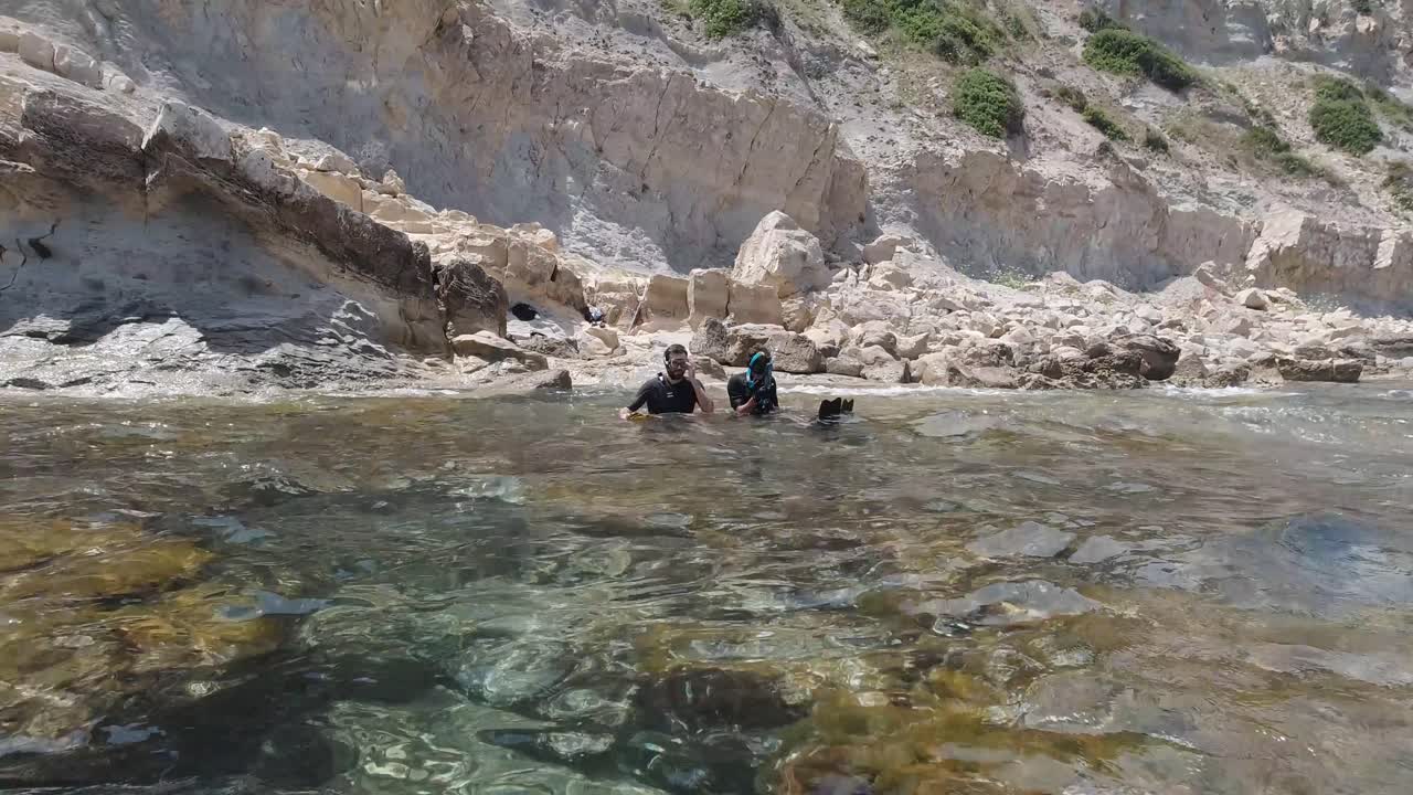 Spearfishers get ready at a rocky shore line in crystal clear waters in the mediterranean sea