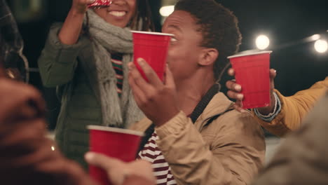 group-of-friends-making-toast-drinking-enjoying-rooftop-party-celebration-at-night-young-multi-ethnic-people-having-fun-socializing-hanging-out-on-weekend