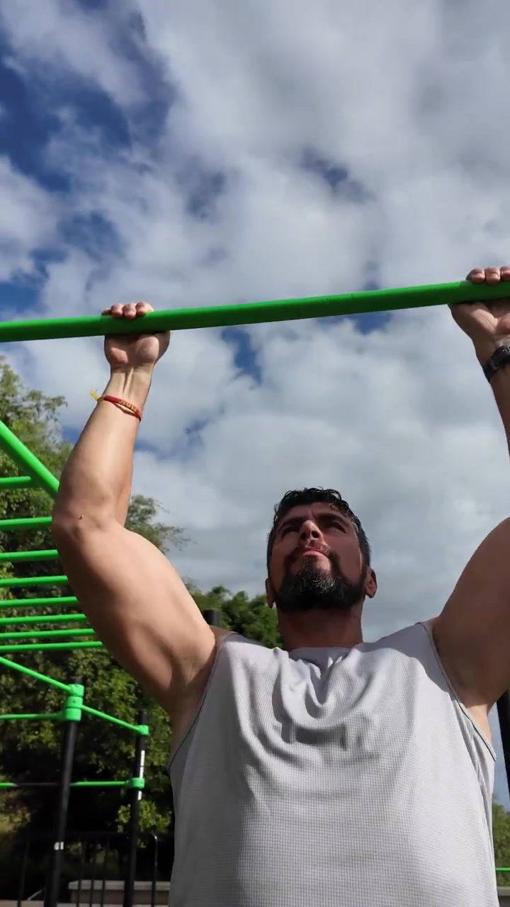 Young man doing pull-ups on bar in outdoor park workout