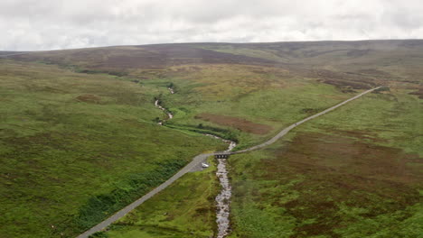 Toma-Aérea-De-La-Carretera-Y-El-Río-En-El-Parque-Nacional-De-Las-Montañas-Wicklow-En-Irlanda