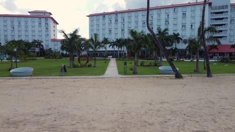 Low-angle-drone-shot-of-beachfront-and-garden-area-of-Crown-Plaza-Hotel,-Saipan