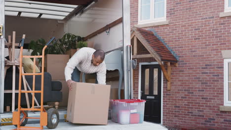 Hombre-Descargando-Cajas-Del-Camión-De-Mudanzas-Fuera-De-Casa-Nueva-El-Día-De-La-Mudanza