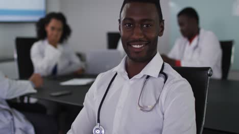 portrait of african american male doctor sitting in meeting room looking to camera smiling