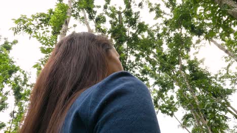 portrait of a young woman looking around in the forest at daytime. low angle