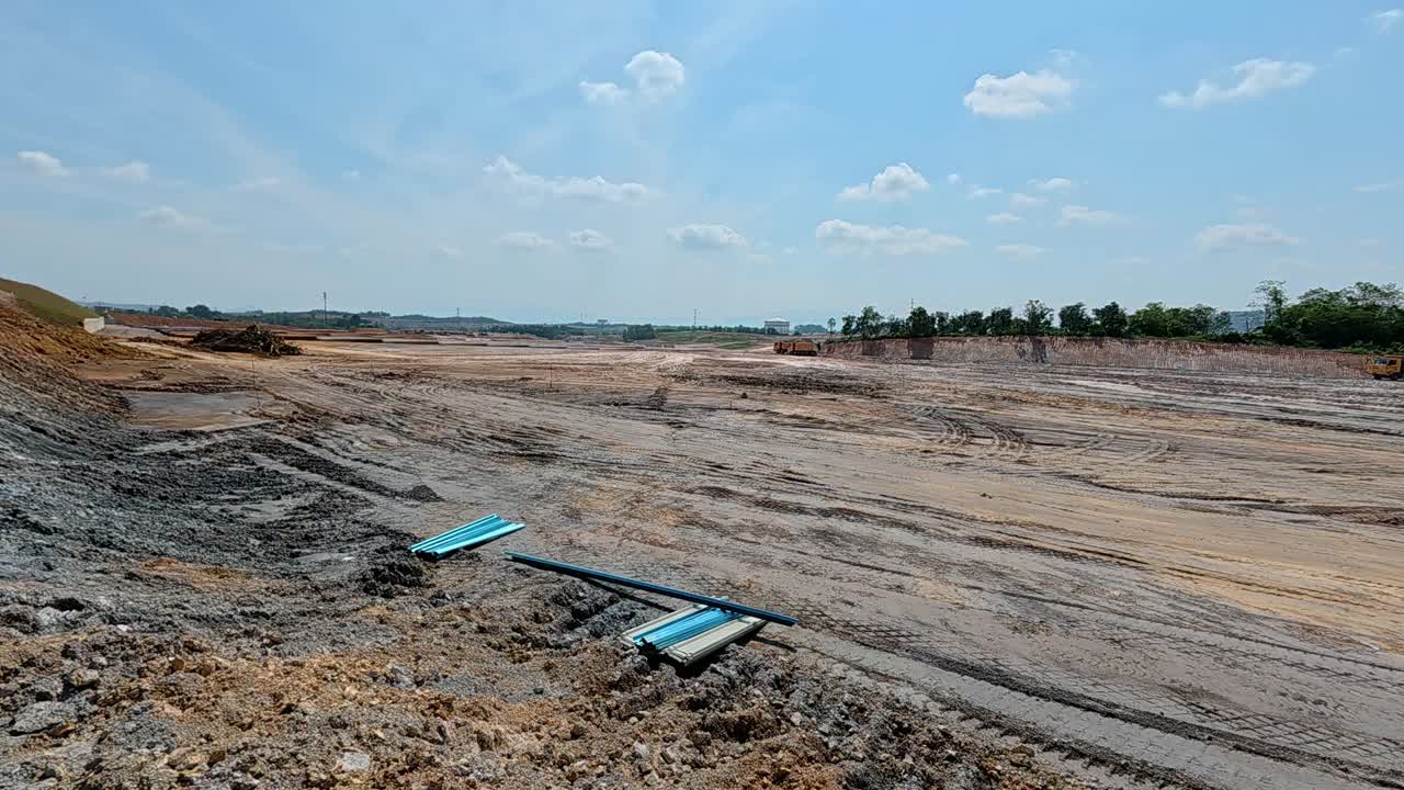 Extensive earthworks at a large construction site. Heavy machinery is used to level the ground, cutting into hills and filling in ravines to prepare the land for building new homes