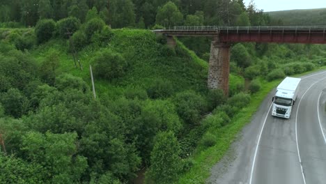 camión en un camino de campo bajo un puente, paisaje forestal